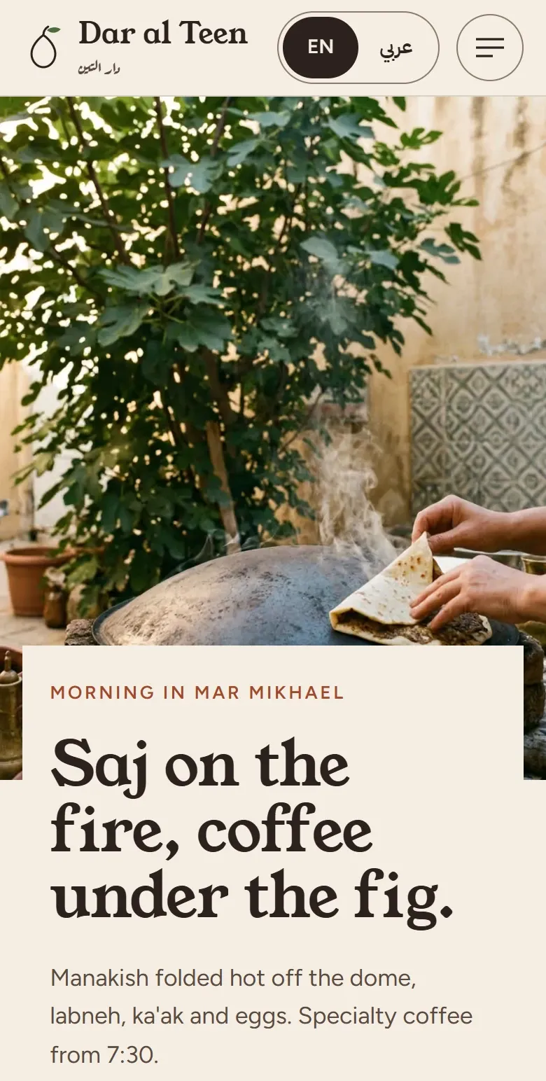 Home screen of the Dar al Teen concept site in the morning: manakish folded on the saj under a fig tree, and the headline "Saj on the fire, coffee under the fig."